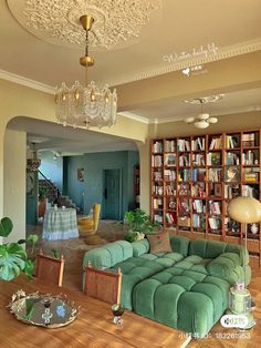 a living room filled with green couches and bookshelves next to a dining table