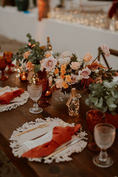 a wooden table topped with lots of different types of flowers and place settings on top of it