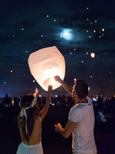 two people are releasing lanterns into the sky