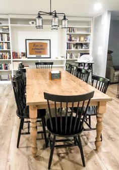 a wooden table surrounded by black chairs and bookshelves