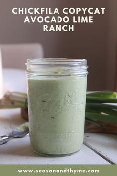 a glass jar filled with green food sitting on top of a table next to a spoon