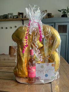 a bottle of wine sitting on top of a table next to some foil wrapped balloons