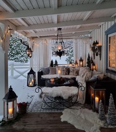 a porch covered in snow with christmas lights and decorations on the outside wall, along with candles