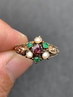 Delicate and Unique Victorian ring  Circa 1857 Many hallmarks - including 375 beautiful goldwork...a lost art! Hallmarked Birmingham 1857  3 Green Emeralds with surface wear  measuring approx. 2.25mm round faceted...sold to me as genuine but I think they may be paste (glass) which was customary in this era 3 pearls 3mm Genuine 4mm cushion cut garnet with surface crack...see photos 1 gram weight Natural patina ( antiquing) which could be cleaned but I leave the pieces as I find them unless they a Victorian Yellow Gold Emerald Ring, Victorian Emerald Ring In Yellow Gold, Victorian Gold Emerald Ring, Antique Multi-stone Ruby Ring, Victorian Style Collectible Emerald Ring, Victorian Wedding Ring, Dope Jewelry Accessories, Vintage Jewelry Antique, Victorian Ring