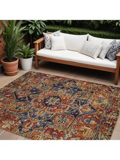 an area rug with various colors and patterns on the floor next to potted plants