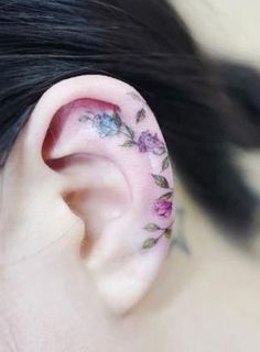 a close up of a person's ear with flowers tattooed on the inside of it