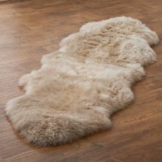 a sheepskin rug is laying on the floor in front of a wooden flooring