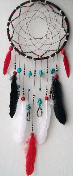 a dream catcher with feathers and beads hanging from it's side on a wall