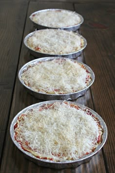 three pizza pies sitting on top of metal pans covered in parmesan cheese