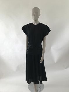 Gorgeous 1940's black crepe cocktail dress with satin waist belt and satin sleeve details. Matching Crepe belt is a bit brittle. Metal zipper up the back and waist gather in the back.Size medium: Bust: 38"Waist: 28"Hips: max 48"47.5" shoulder to hemBelt: 36" long Black Belted Dress For Party, Black Belted Evening Dress, Fitted Black Belted Dress For Evening, Fitted Short Sleeve Belted Evening Dress, Short Sleeve Belted Evening Dress, Fitted Belted Dress With Short Sleeves For Evening, Evening Dress With Belt And Short Sleeves, Elegant Black Belted Dress For Evening, Elegant Black Belted Evening Dress