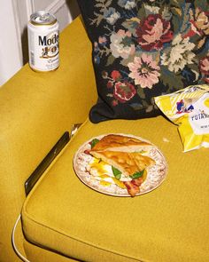 a plate of food sitting on top of a yellow chair next to a can of soda