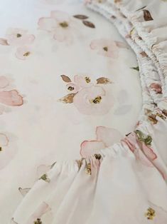 an unmade bed with pink flowers and ruffles on the bedspread