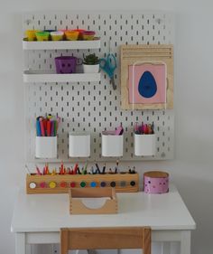 a white desk topped with lots of crafting supplies next to a wall mounted shelf