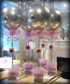 pink and silver balloons are on display in front of a fireplace