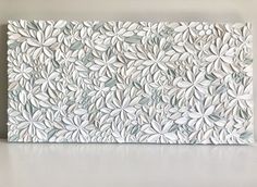 a white wall sculpture with leaves on it