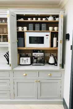 a kitchen with gray cabinets and white appliances on the counter top, along with coffee maker and toaster