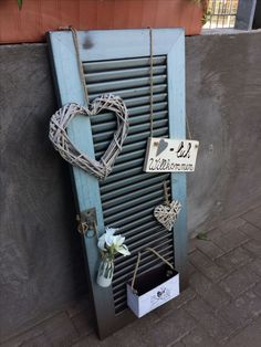 a heart shaped sign hanging on the side of a wall next to a vase with flowers