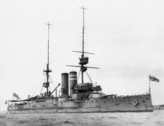 an old photo of a battleship in the water with two flags on it's mast