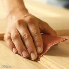 a person wiping down some wood with a sanding cloth on top of the table