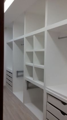 an empty room with white shelves and drawers