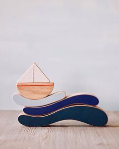 a wooden toy boat sitting on top of a wooden table next to a white wall