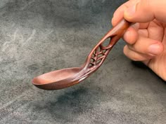 a person holding a wooden spoon in their hand on a gray surface with other items nearby