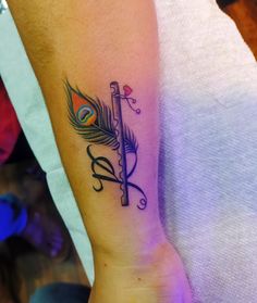 a woman's arm with a feather and cross tattoo on the left side of her arm