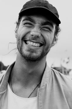 a black and white photo of a man with a hat on smiling at the camera