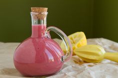 a pink vase with some bananas on the table