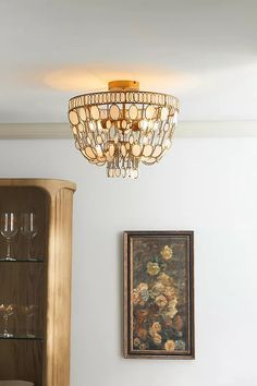 a chandelier hanging from the ceiling in a living room next to a painting