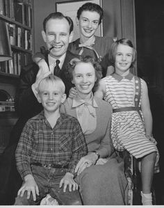 an old black and white photo of a family posing for a picture in front of bookshelves