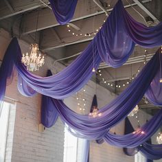 purple draping hanging from the ceiling in a room with chandeliers and lights