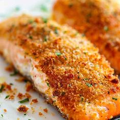 two pieces of fish on a plate with seasoning sprinkled on it's side