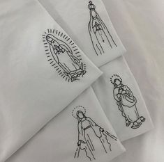 three embroidered napkins with pictures of jesus and mary in black ink on white paper