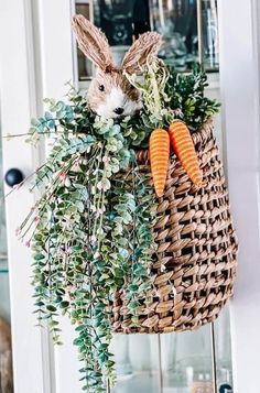 a basket filled with carrots and greenery on top of a counter next to a door