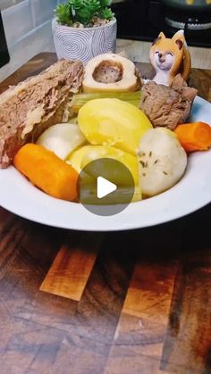 a white plate topped with different types of food on top of a wooden table next to a potted plant