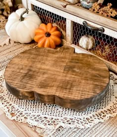 a wooden cutting board sitting on top of a table next to pumpkins and gourds