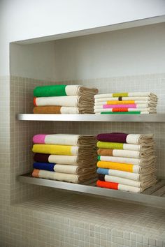 towels are stacked up on shelves in the bathroom, with one folded and two unrolled