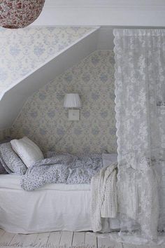 a bed sitting under a window next to a white wallpaper covered ceiling in a bedroom