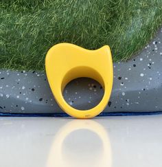 a yellow plastic object sitting on top of a white surface next to grass and dirt