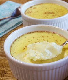 two white bowls filled with soup on top of a wooden table