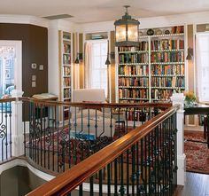 a living room filled with lots of books on top of a book shelf next to a stair case