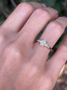 a woman's hand with a diamond ring on top of her finger and the other hand holding an engagement ring