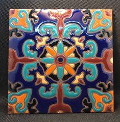 a blue and orange tile with an intricate design on the bottom, sitting on a gray surface