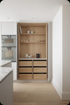 an empty kitchen with wooden cabinets and marble counter tops, along with wood flooring