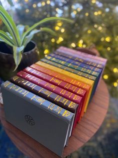 a stack of books sitting on top of a table next to a potted plant