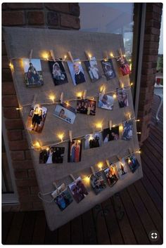 a bulletin board with pictures and lights hanging from it's sides on a wooden deck