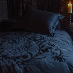 a bed with blue comforter next to a lit candle