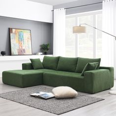 a living room with a large green sectional couch and white rugs on the floor