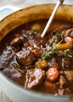 a wooden bowl filled with beef stew and carrots